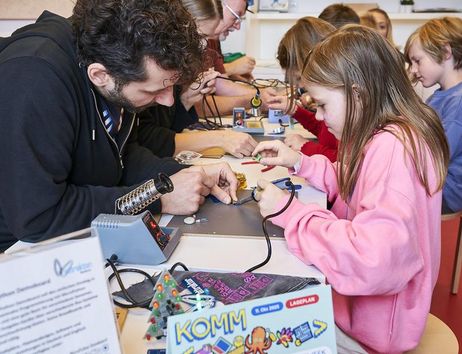 Mehrere Kinder, die mit dem Lötkolben Sachen reparieren