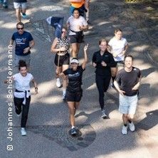 Eine Gruppe von Menschen joggt auf einem Weg im Freien.