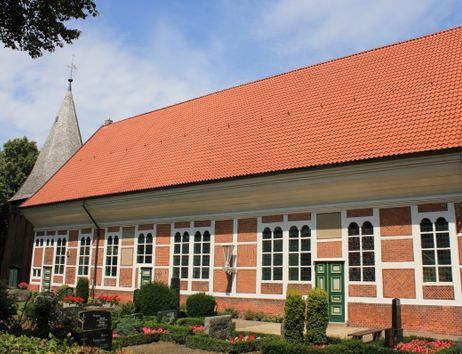 Außenansicht der Dreieinigkeitskirche Allermöhe mit rotem Ziegeldach und Fachwerkfassade.