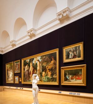 Innenansicht eines Museums mit Gemälden und einer Skulptur.