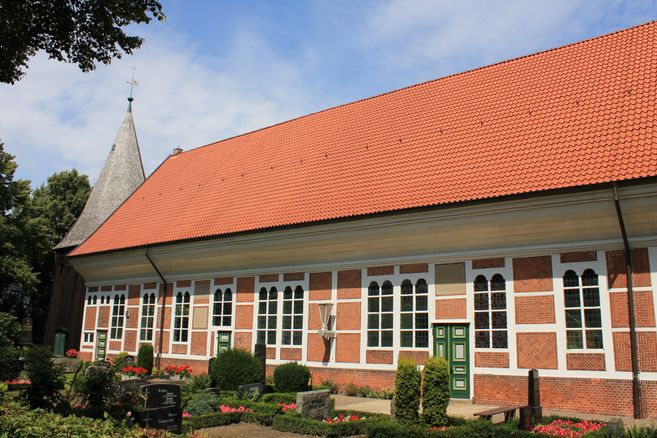 Außenansicht der Dreieinigkeitskirche Allermöhe mit rotem Ziegeldach und Fachwerkfassade.