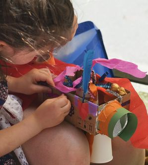 Kind bastelt ein buntes Modell aus Pappe und Papier.