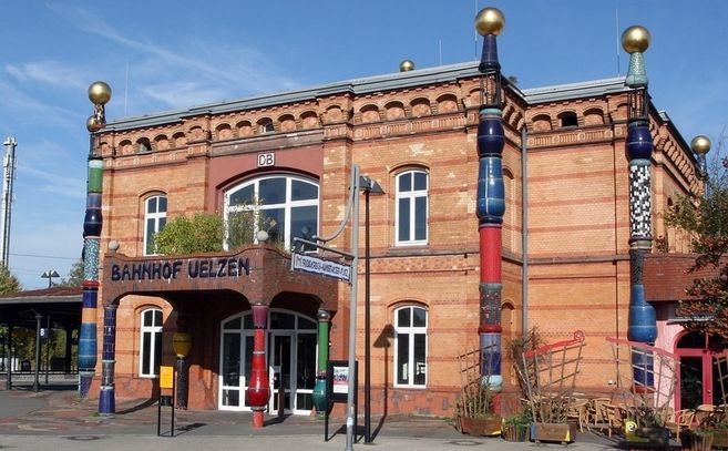 Außenansicht des Hundertwasser-Bahnhofs in Uelzen mit bunten Säulen und goldenen Kugeln.