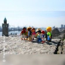 Spielzeugfiguren stehen auf einem Felsen mit einem Hafen im Hintergrund.