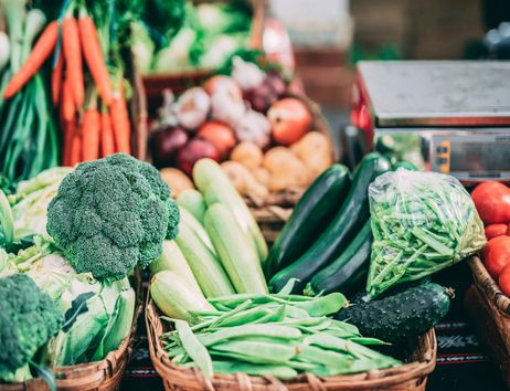 Frisches Gemüse auf einem Wochenmarkt, darunter Brokkoli, Karotten, Zucchini und Tomaten.
