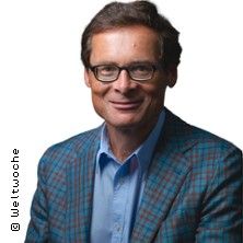 Ein Mann mit Brille und kariertem Sakko lächelt in die Kamera.