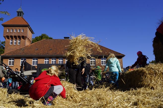 Kinder spielen auf einer Strohballenburg auf dem Alsterdorfer Markt.