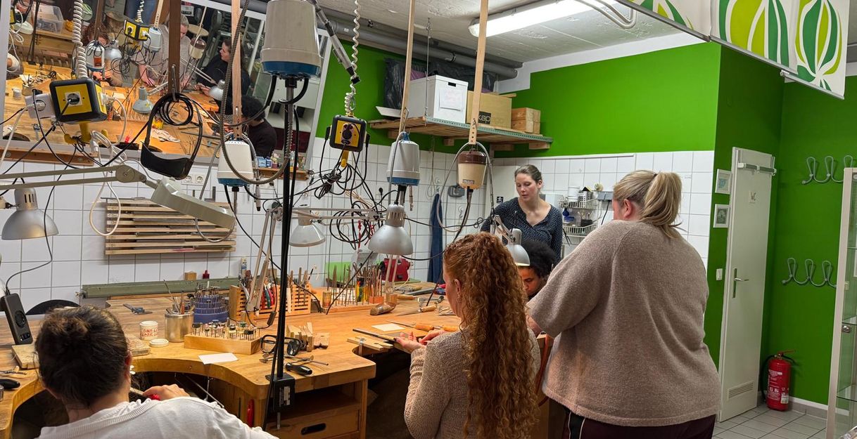 Personen stehen an einem Tisch und schmieden einen Ring