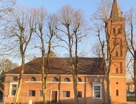 Seitenansicht der Marienkirche in Quickborn mit Bäumen im Vordergrund.