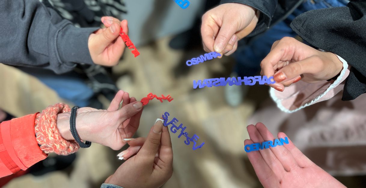 Mehrere Hände halten bunte 3D-gedruckte Namensschilder in einem Kreis.