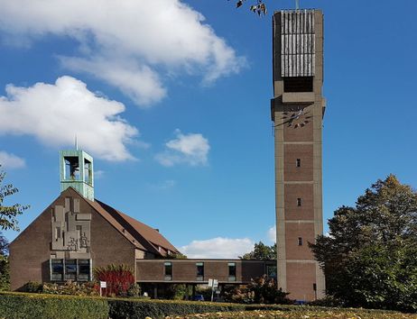 Außenansicht der Christus-Kirche in Wandsbek mit hohem Glockenturm und blauem Himmel im Hintergrund.