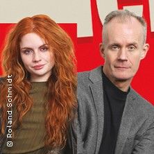 Ein Mann und eine Frau stehen nebeneinander vor einem roten Hintergrund.