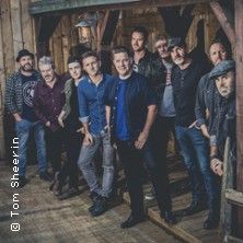 Eine Gruppe von zehn Personen steht in einem rustikalen Holzgebäude und posiert für ein Foto.