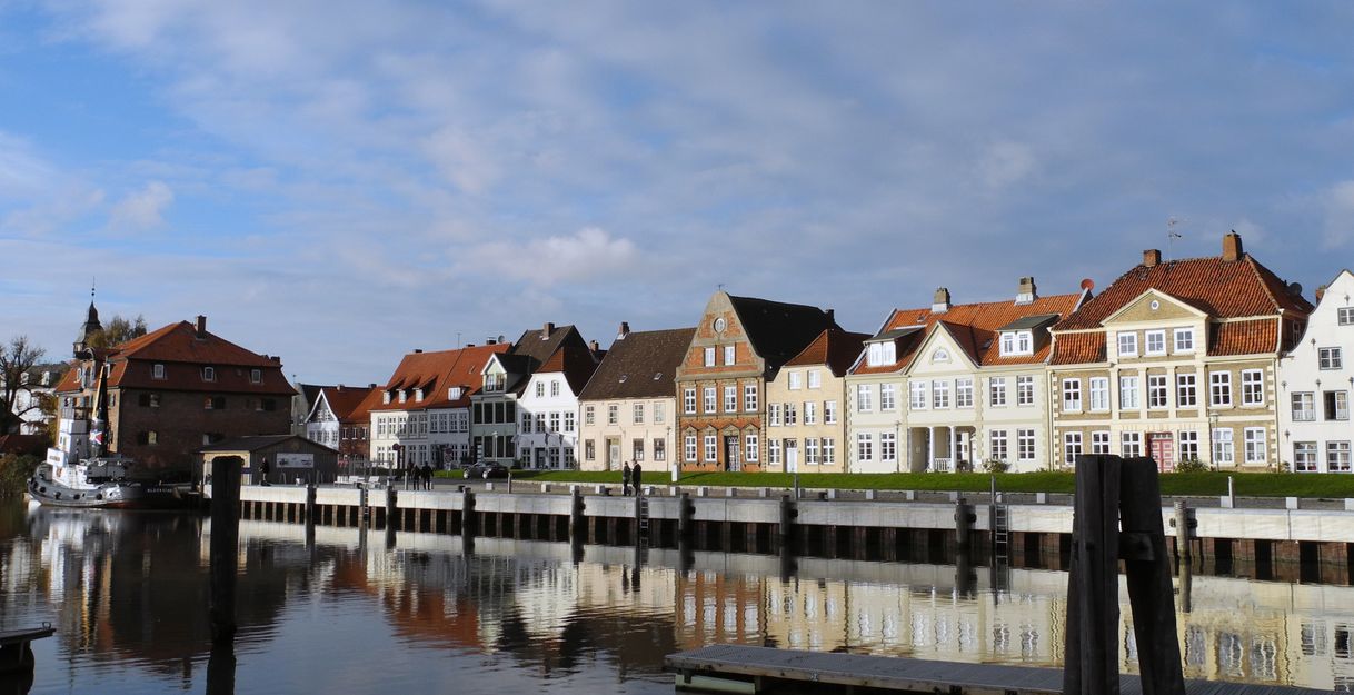 Historische Gebäude am Binnenhafen von Glückstadt mit Spiegelung im Wasser.