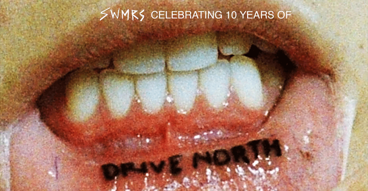 Nahaufnahme eines Mundes mit einem Tattoo auf der Innenseite der Unterlippe, das "DRIVE NORTH" sagt. Oben steht "SWMRS CELEBRATING 10 YEARS OF".
