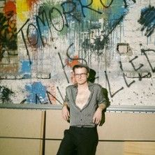 Person lehnt an einer Wand mit Graffiti und dem Schriftzug 'Tomorrow is cancelled'.