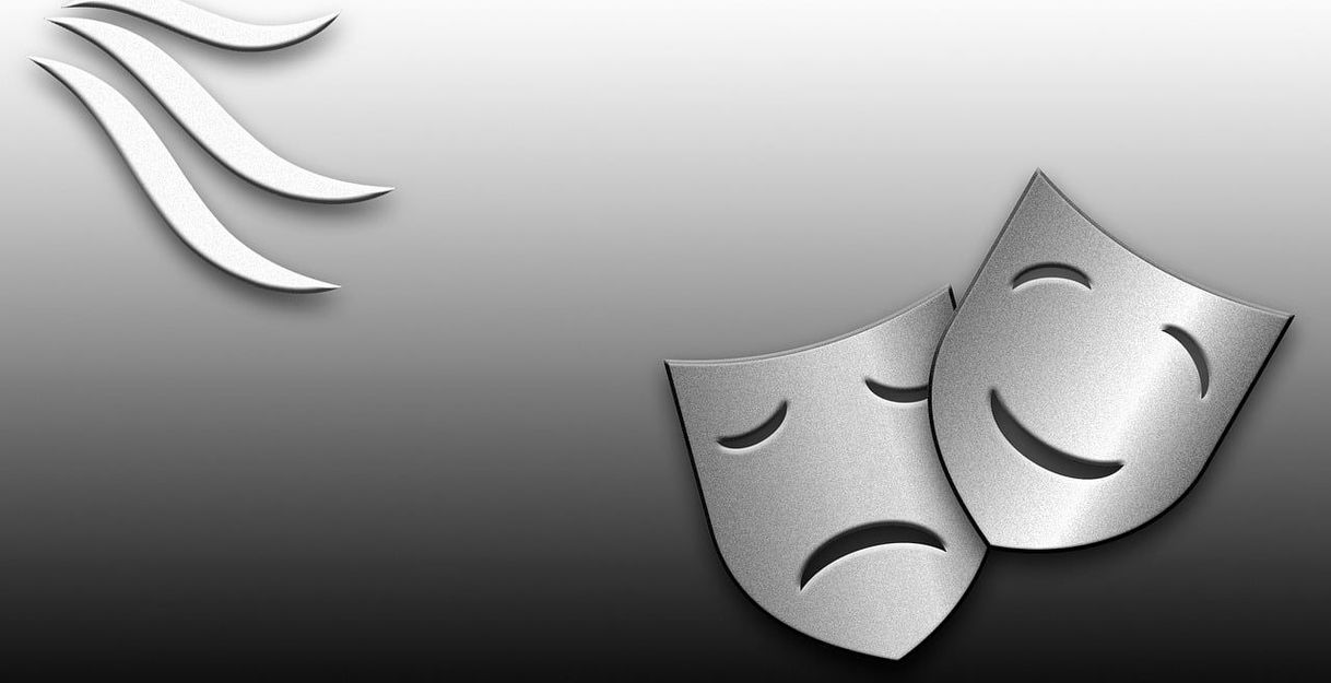 Zwei silberne Theatermasken, eine lachend und eine traurig, auf grauem Hintergrund.