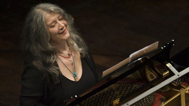 Eine Frau spielt lächelnd Klavier auf einer Bühne.