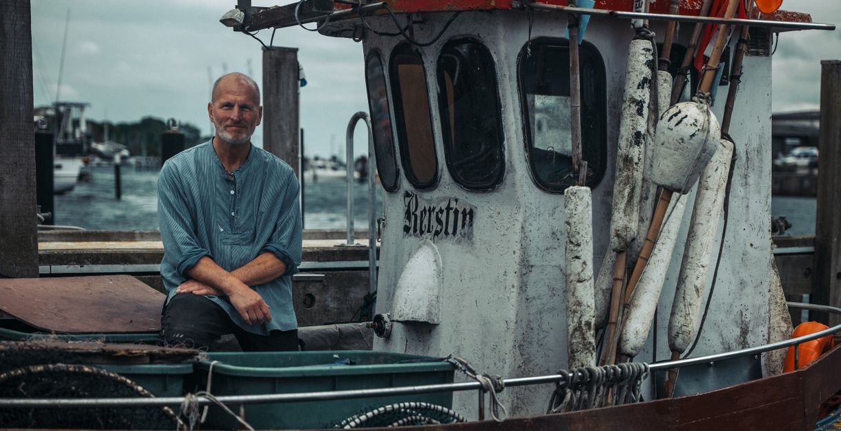 Ein Fischer sitzt auf einem Boot im Hafen von Neustadt in Holstein.
