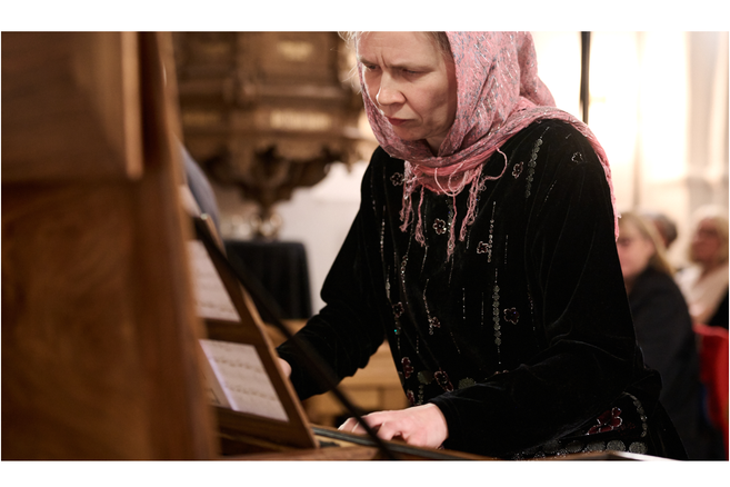 Eine Frau mit Kopftuch spielt konzentriert Klavier bei einem Konzert.