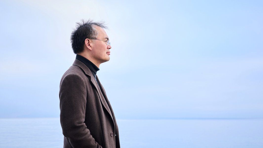 Ein Mann im Profil, der auf das Meer blickt, vor einem blauen Himmel.