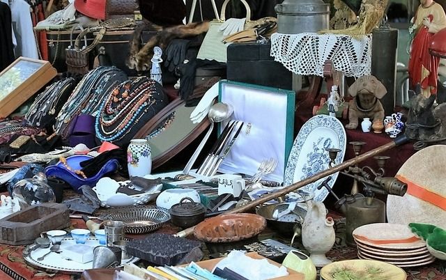 Ein Flohmarktstand mit einer Vielzahl von antiken und gebrauchten Gegenständen, darunter Schmuck, Geschirr und Dekorationsartikel.