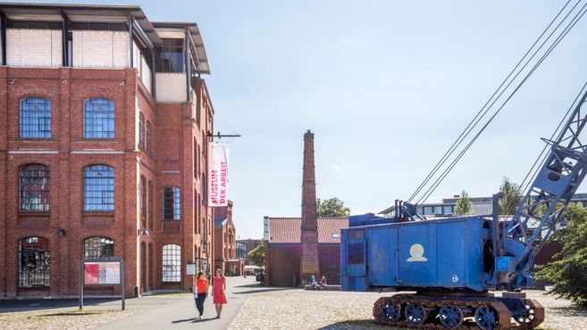 Außenansicht des Museums der Arbeit mit rotem Backsteingebäude und blauem Kran.