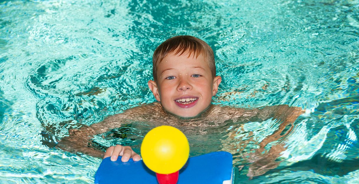 Kind mit einem Schwimmbrett im Wasser