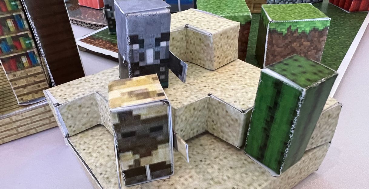 Papiermodelle von Minecraft-Charakteren und Blöcken auf einem Tisch.