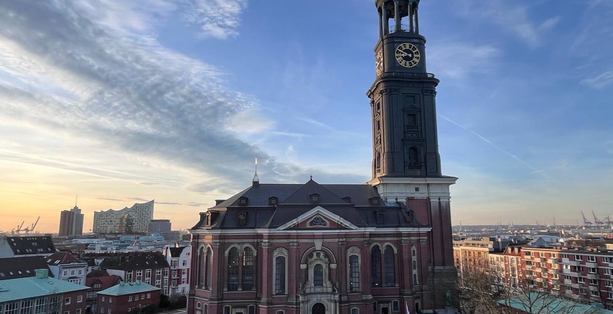 St. Michaelis Kirche in Hamburg bei Sonnenuntergang mit der Elbphilharmonie im Hintergrund.