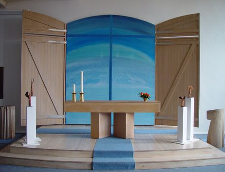 Moderner Kirchenaltar mit blauem Hintergrund und Holzelementen.