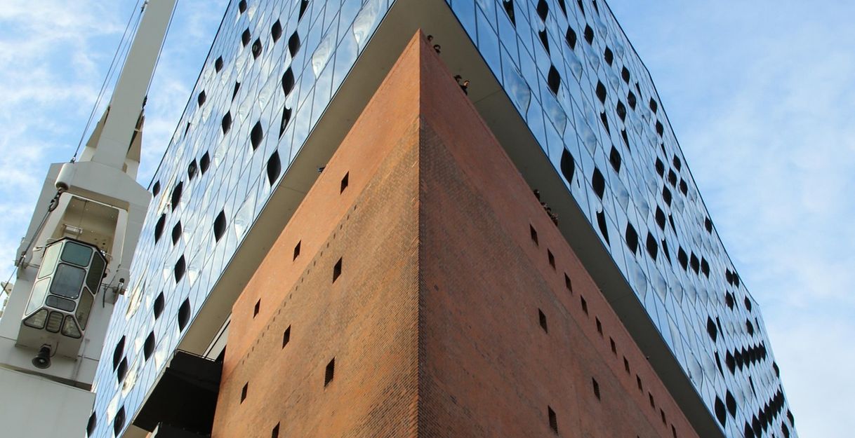 Ansicht der Elbphilharmonie in Hamburg mit rotem Backsteinsockel und gläserner Fassade.