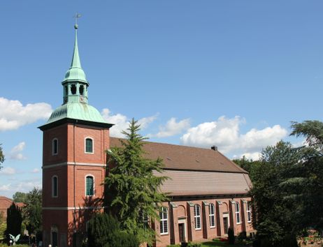 Kirche St. Pankratius in Ochsenwerder mit rotem Backstein und grünem Turm unter blauem Himmel.