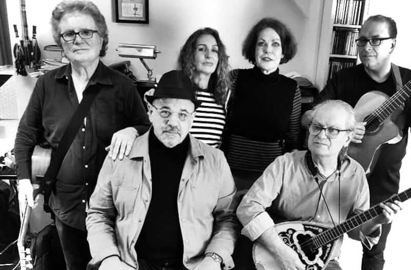 Schwarz-weiß Foto von sechs Personen mit Musikinstrumenten in einem Raum.