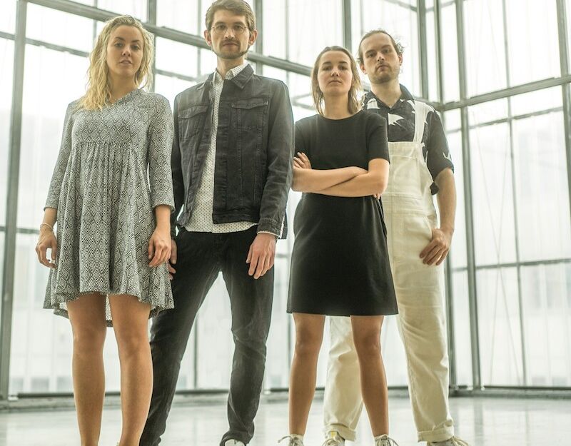 Vier Personen stehen in einem modernen, lichtdurchfluteten Raum.