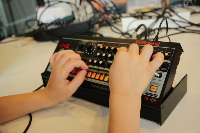 Kinderhände bedienen einen kleinen Synthesizer