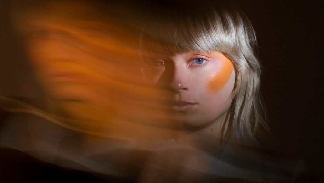 Porträt einer Frau mit verschwommenen, orangefarbenen Lichteffekten.