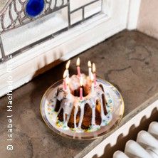 Kleiner Kuchen mit Kerzen auf Fensterbank.