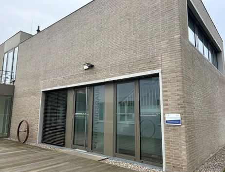 Modernes Gebäude mit Glasfront und Backsteinfassade.