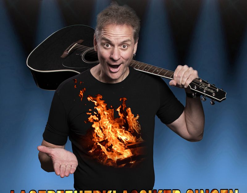 Mann mit Gitarre und Lagerfeuer-T-Shirt vor blauem Hintergrund.