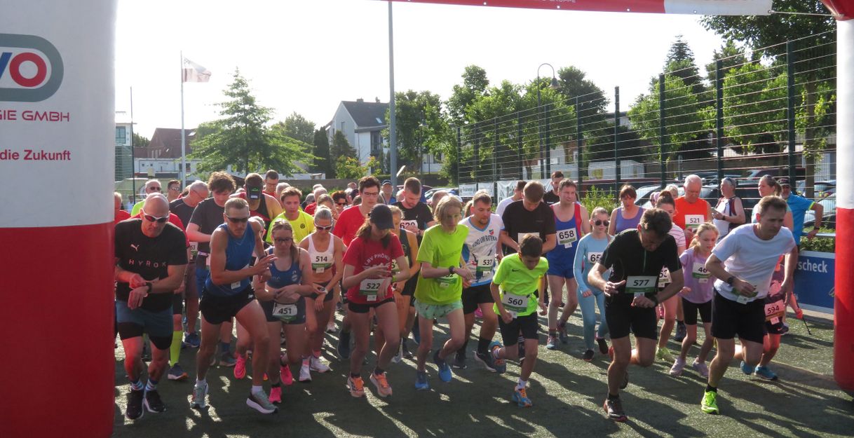 Gruppe von Läufern startet bei einem Jogginglauf in Pönitz unter einem roten Startbogen.