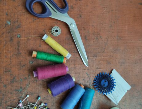 Schere, Garn in gelb,grün,pink,lila,blau und Türkis. Ein Haufen Stecknadeln.
