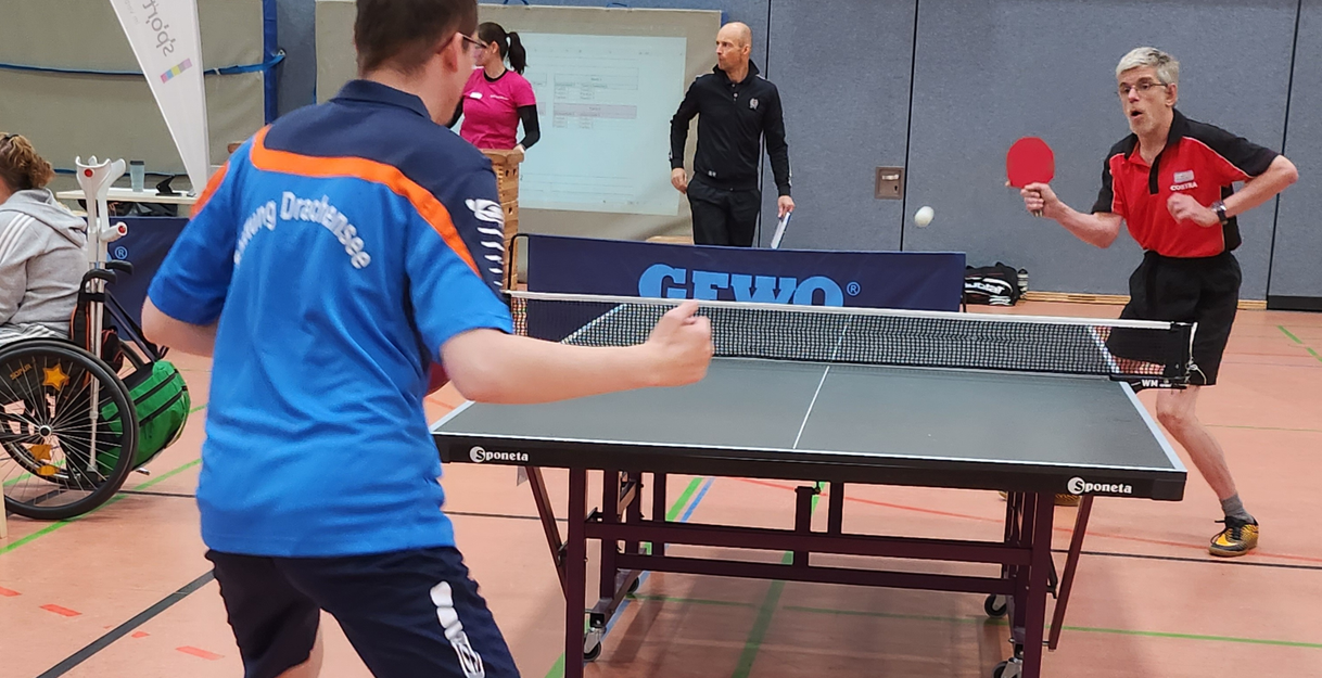 Zwei Personen stehen an einer Tischtennisplatte
