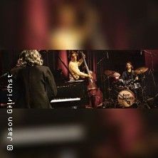 Eine Jazzband spielt auf einer Bühne mit einem Pianisten, einem Bassisten und einem Schlagzeuger. Das Schlagzeug trägt den Schriftzug 'Jazz Sabbath'.