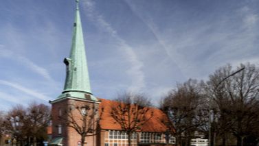 Kirche St. Johannis in Hamburg-Eppendorf mit spitzem Turm und rotem Dach.