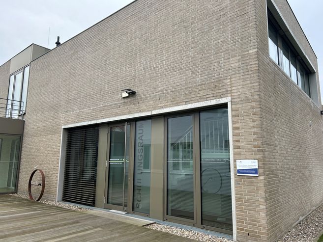 Modernes Gebäude mit Glasfront und Backsteinfassade.