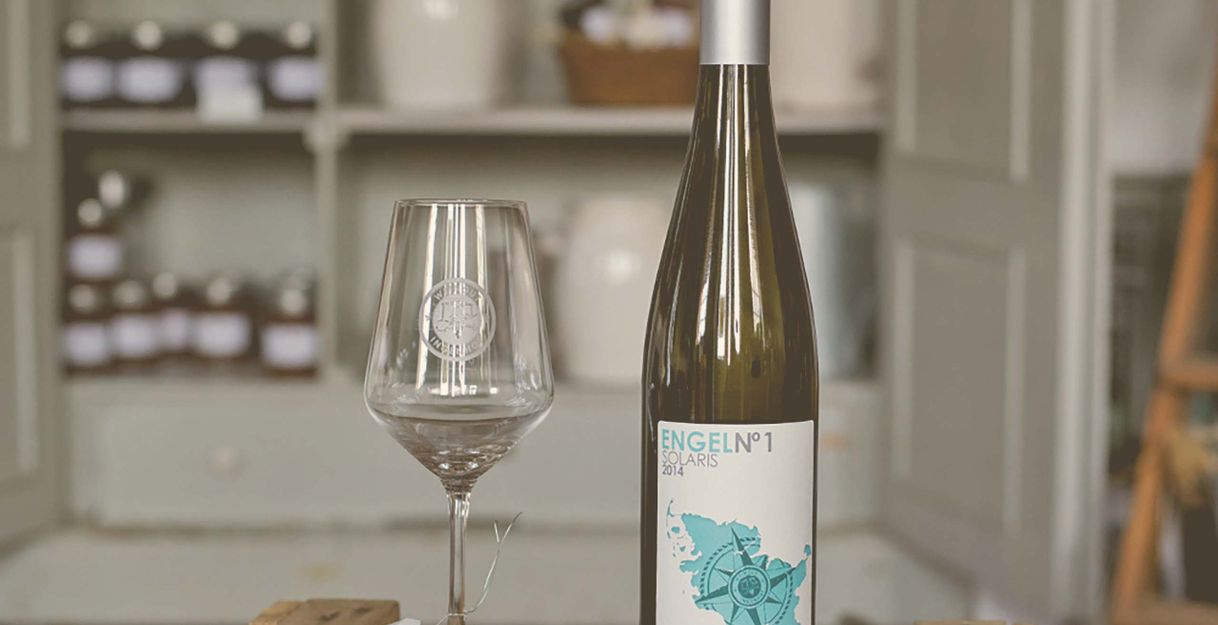 Weinflasche und Glas auf einem Holztisch vor einem Regal.