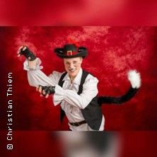 Person in einem gestiefelten Kater-Kostüm vor rotem Hintergrund.