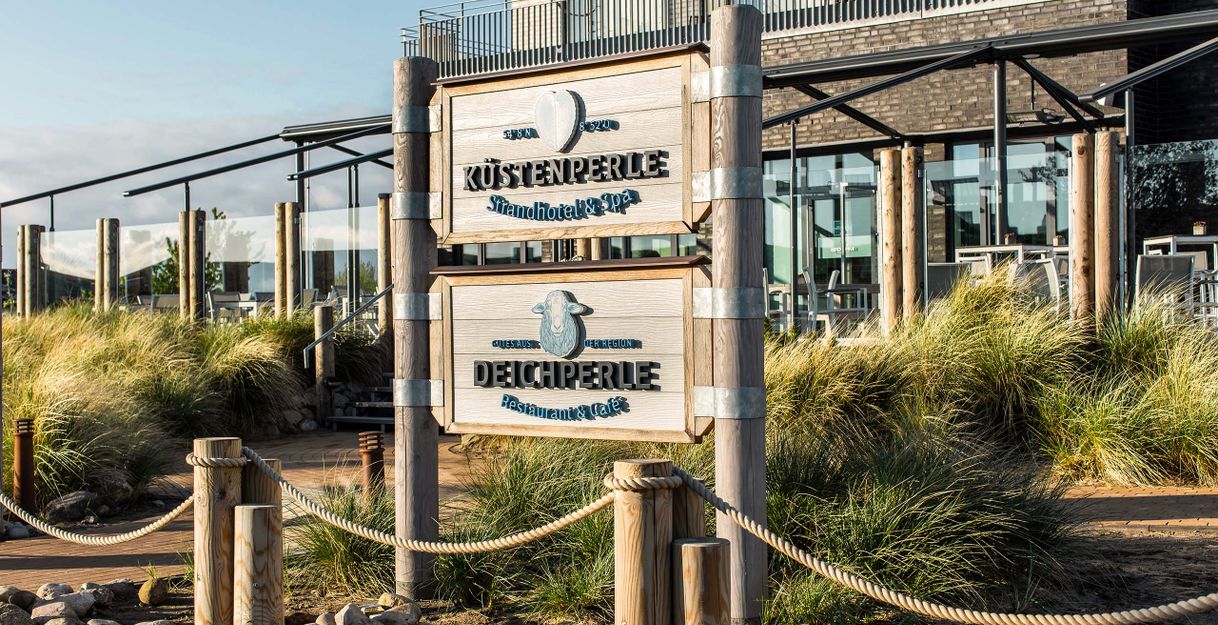 Eingangsschild des Küstenperle Strandhotel & Spa und Deichperle Restaurant & Café.