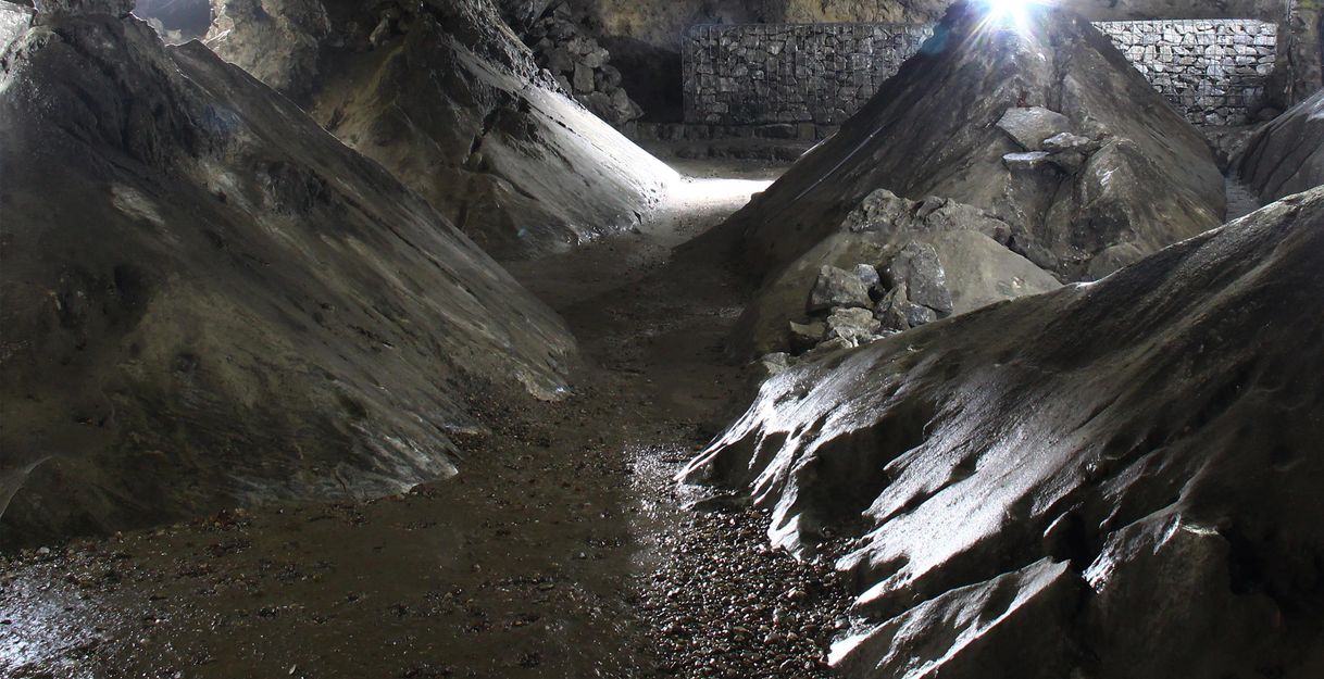 Innenansicht einer beleuchteten Kalkberghöhle mit steinigen Wänden und Boden.